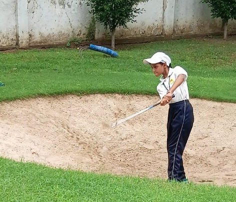 Student practicing bunker shot on golf course
